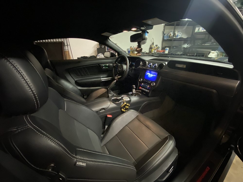 Black leather seats and center console of a coupe inside a garage at night